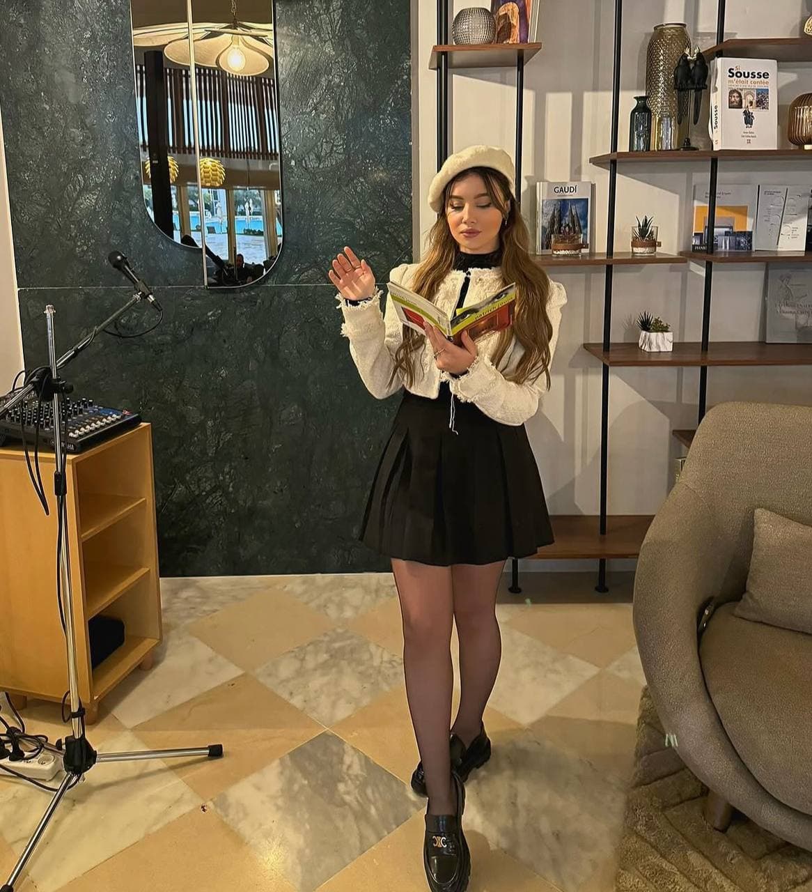 Melissa Belhouchet reading in a beret and cropped tweed jacket